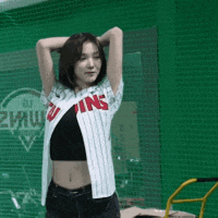 a woman in a twins jersey stands in front of a green fence