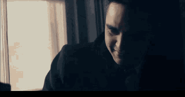a man in a suit and tie is looking out a window