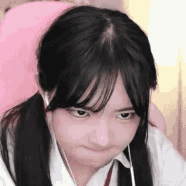 a girl with pigtails and earphones is making a funny face .