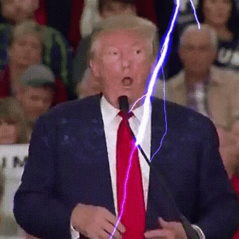 a man in a suit and tie is speaking into a microphone while a lightning bolt is coming out of his mouth .