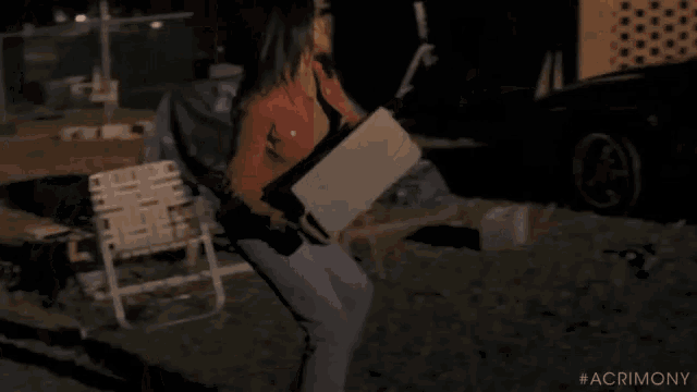 a woman is standing next to a broken car in a garage .
