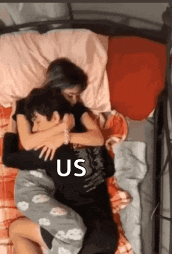 a boy and a girl are hugging each other while laying on a bed .