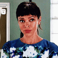 the woman is wearing a blue floral dress and making a funny face .