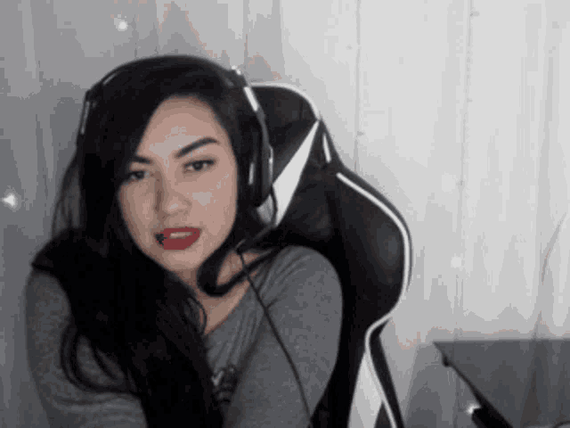 a woman wearing headphones and red lipstick is sitting in a chair