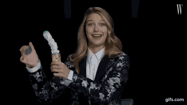 a woman in a floral jacket is holding a can of confetti and laughing .