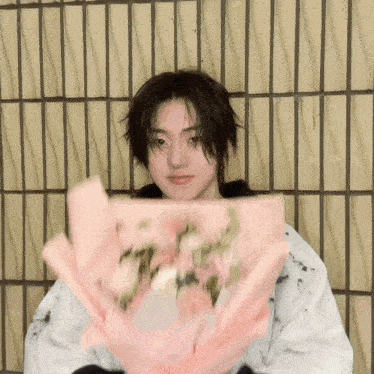 a young man is holding a bouquet of pink flowers .