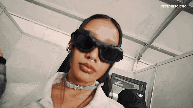 a woman wearing sunglasses and a choker is taking a selfie .