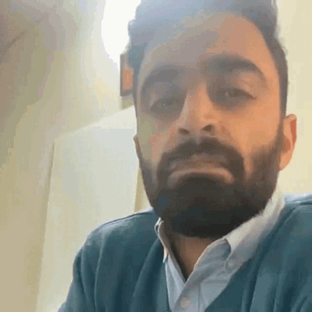 a man with a beard wearing a blue sweater