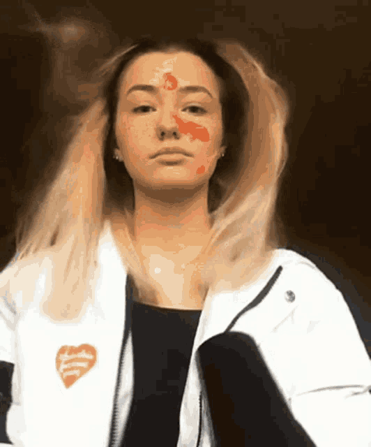 a woman wearing a white jacket with a red heart on the front