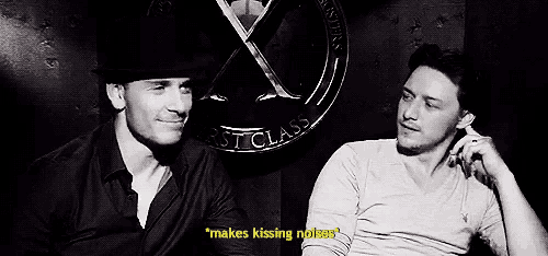 two men are sitting next to each other in front of a sign that says ' makes kissing noises ' .