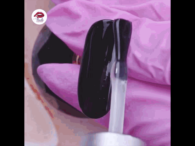 a person wearing pink gloves is holding a bottle of nail polish