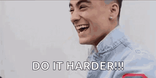 a man in a denim jacket is laughing and saying `` do it harder ! ''