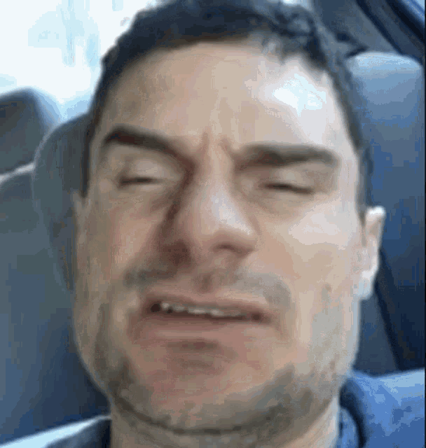 a man is making a funny face while sitting in a car .