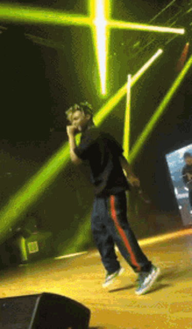 a man singing into a microphone on a stage with green lights