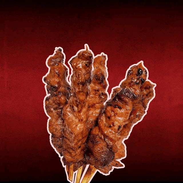 a bunch of chicken skewers on a stick on a red background