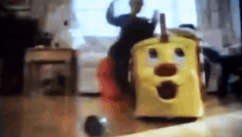 a blurry picture of a person playing with a yellow toy train in a living room .