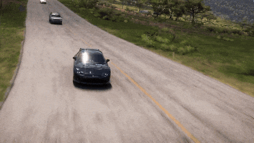 a few cars are driving down a road with trees in the background