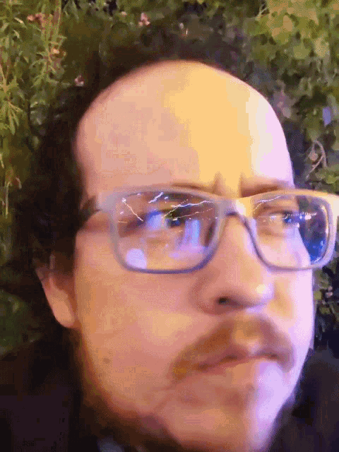 a man with glasses and a beard is making a face