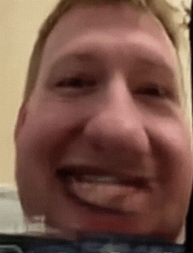 a close up of a man 's face smiling with his tongue out