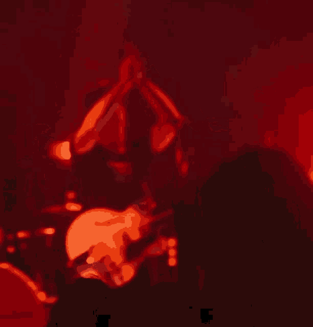 a man playing a guitar in front of a microphone in a dark room