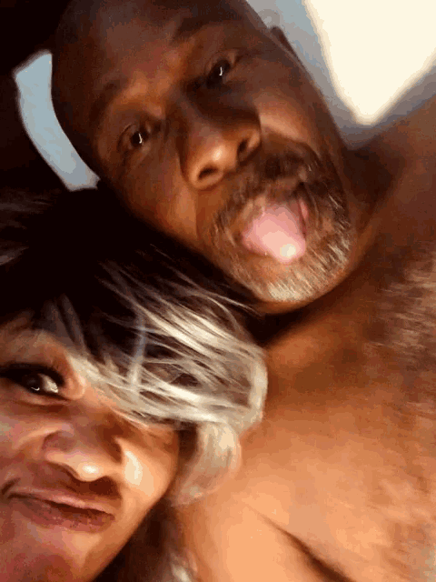 a man and a woman are posing for a picture and the woman is sticking her tongue out