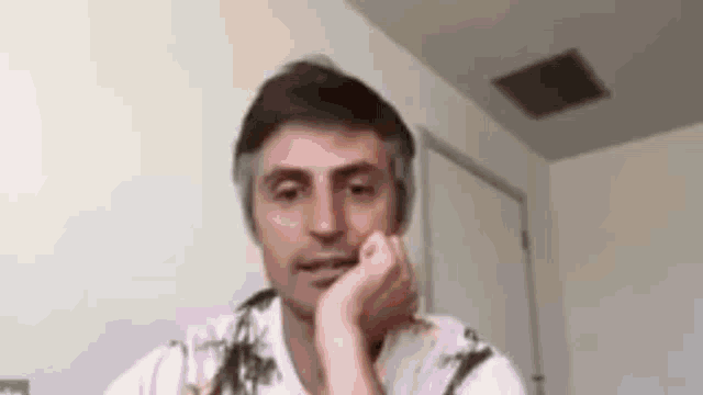 a man is sitting at a table with his hand on his chin .