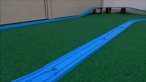 a yellow and white toy train is going down a track