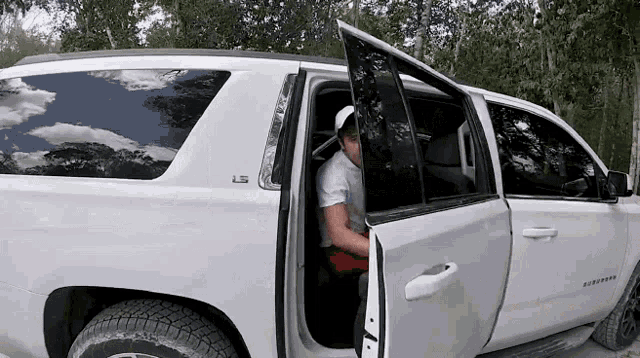 a man getting out of a white suv with the letters ls on the side