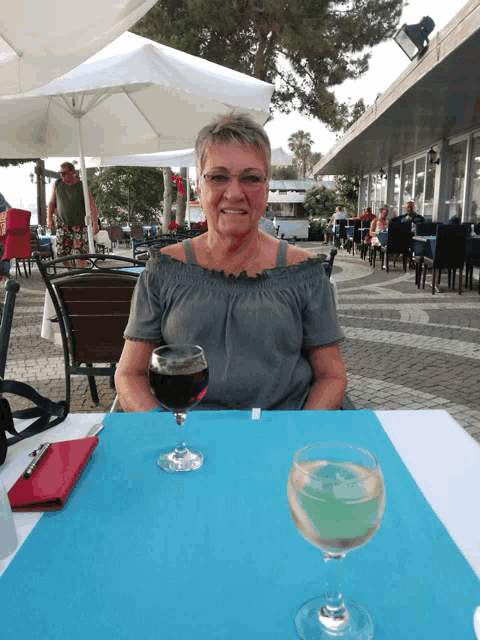 a woman is sitting at a table with a glass of wine