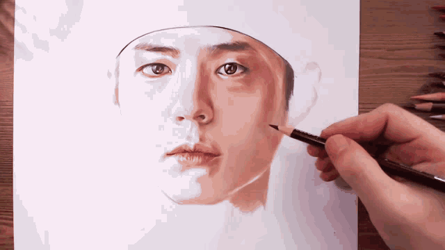a person is drawing a man 's face with a pencil on a piece of paper