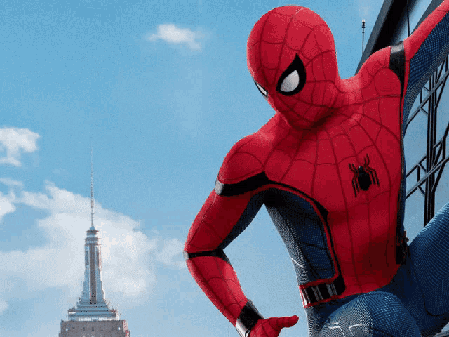 a man in a spiderman costume stands in front of a building