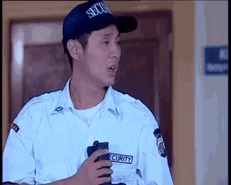 a security guard is talking on a cell phone while wearing a hat that says security .