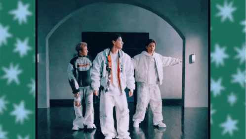 three men in white clothes are dancing in a room with green stars on the wall .