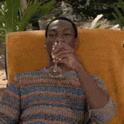 a man in a striped shirt is sitting in a chair holding a wine glass .