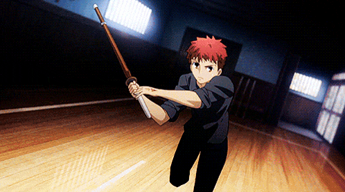 a man in a black shirt is holding a wooden stick in a dark room