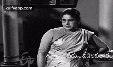 a black and white photo of a woman wearing glasses and a white saree .