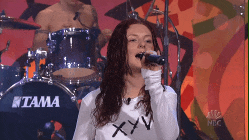 a woman singing in front of a tama drum
