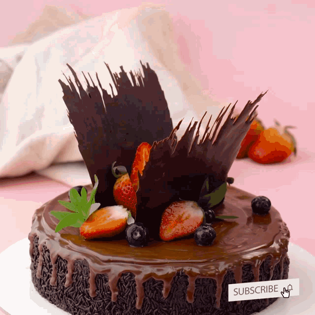 a chocolate cake with strawberries and blueberries and a sign that says " subscribe "
