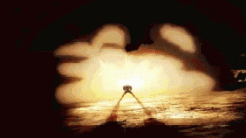 a person standing in front of a large explosion in the dark