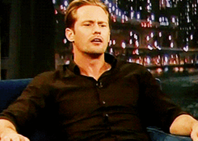 a man in a black shirt sits on a couch