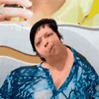 a woman in a blue shirt is taking a picture of herself with her phone .
