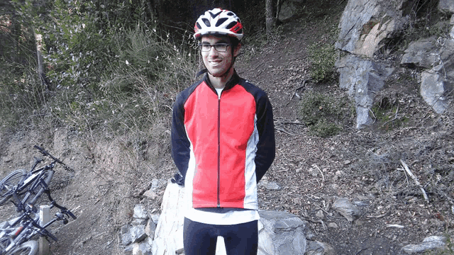 a man wearing a helmet and glasses stands in front of a row of bikes