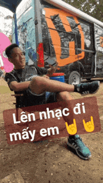 a man sitting in front of a van with a sign that says len nhac di may em on it