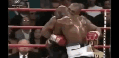 two boxers are fighting in a boxing ring while a crowd watches .