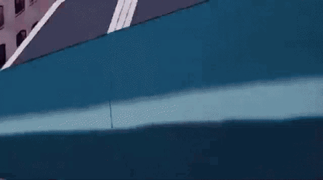 a blue car is driving down a street with a red light behind it