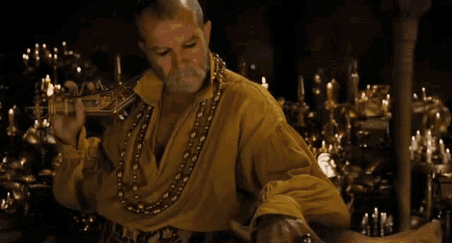 a man in a yellow shirt is holding a sword in his hand