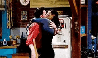 a man is carrying a woman in his arms and they are kissing in a kitchen .