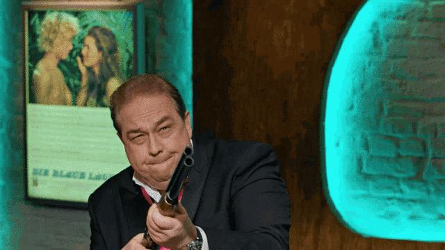 a man in a suit holds a gun in front of a sign that says " der blaue lau "
