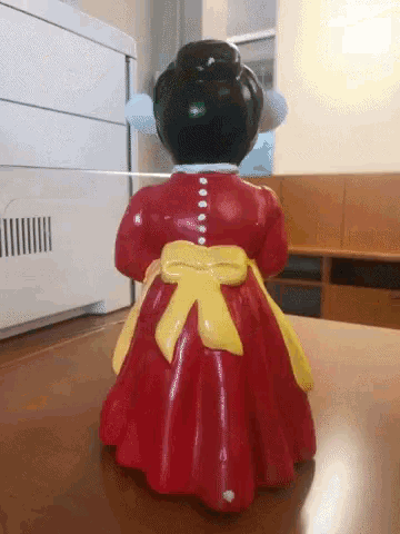 a figurine of a woman in a red dress with a yellow sash around her waist