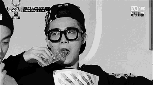 a man wearing glasses and a hat is drinking from a bottle .